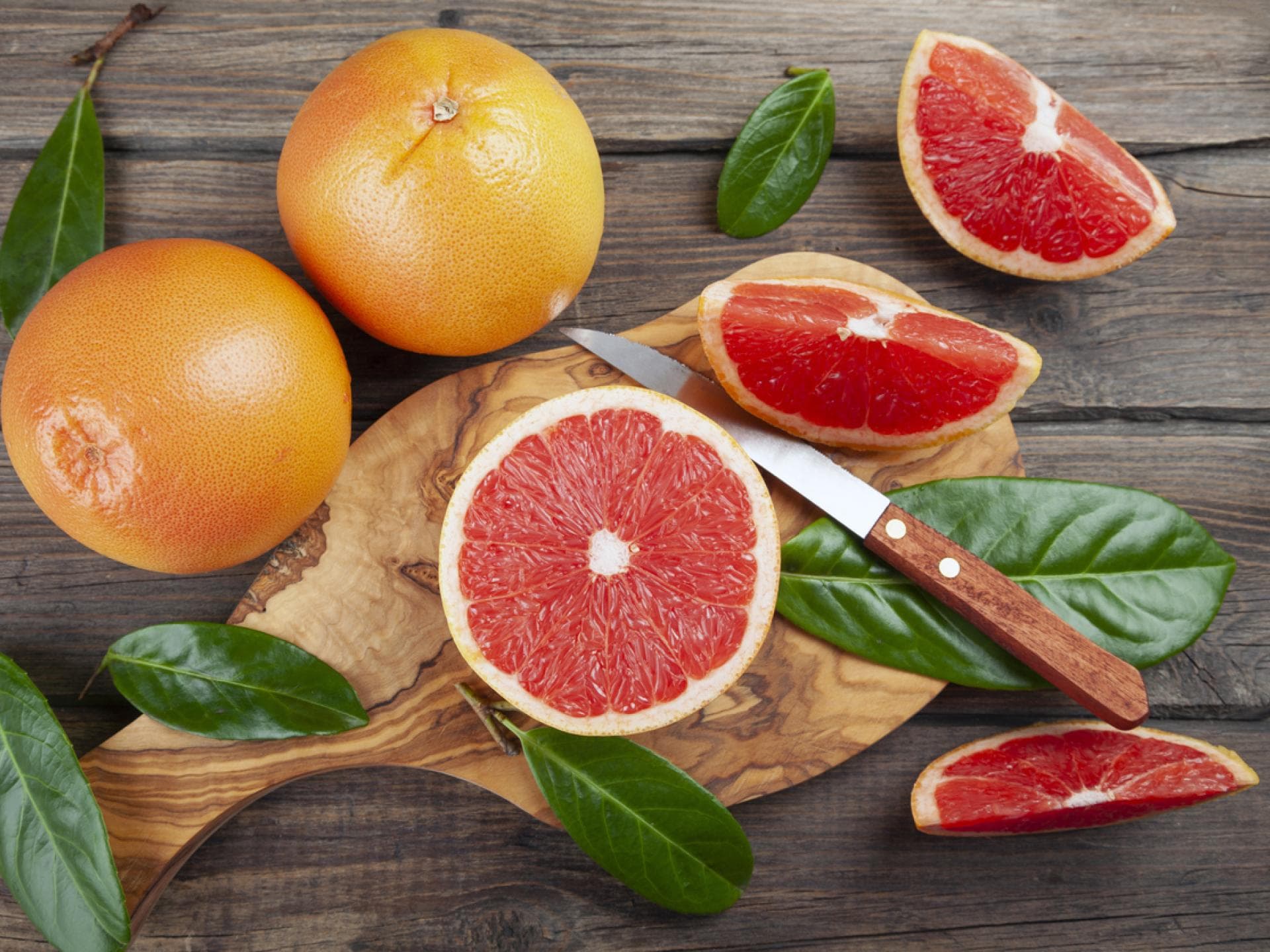 Mehrere Grapefruits mit einem Messer Grapefruit im Ganzen und aufgeschnitten mit einem Messer