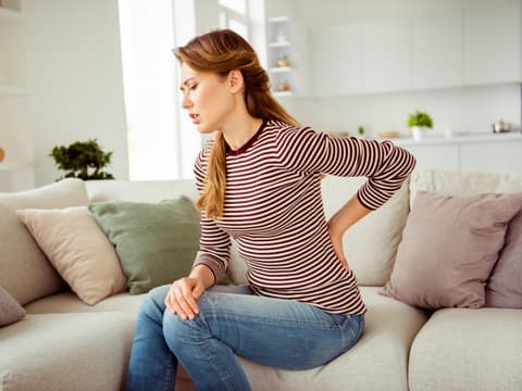 Frau hält sich den Rücken und hat Schmerzen Frau hält sich den Rücken und hat Schmerzen