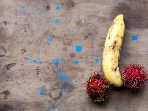 Was kann hinter dem Ausschlag am Penis stecken? Rambutan und Banane symbolisch zu Penis mit Hoden angeordnet