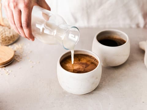 Frau gibt Milch in Kaffee Frau gibt Milch in Kaffee