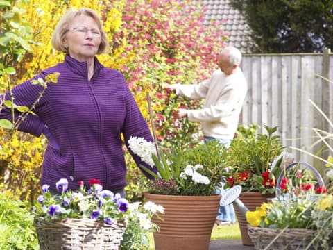 Frau hat Rückenschmerzen nach Gartenarbeit Frau hat Rückenschmerzen nach Gartenarbeit