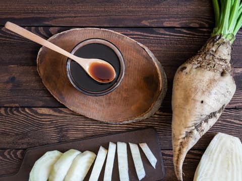 Zuckerrübensirup gilt als gesunde Alternative Draufsicht auf Schälchen mit Zuckerrübensirup und Zuckerrübe auf einem Tisch