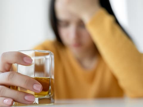 Verzweifelte Frau mit einem Glas Alkohol in der Hand Verzweifelte Frau mit einem Glas Alkohol in der Hand