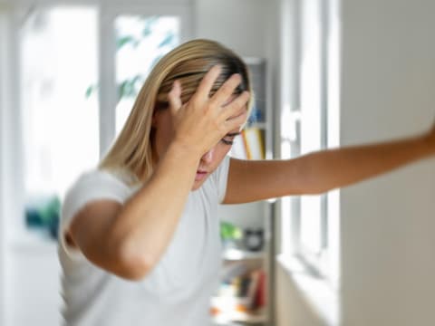 Frau fühlt sich unwohl und stützt sich an der Wand ab Frau fühlt sich unwohl und stützt sich an der Wand ab