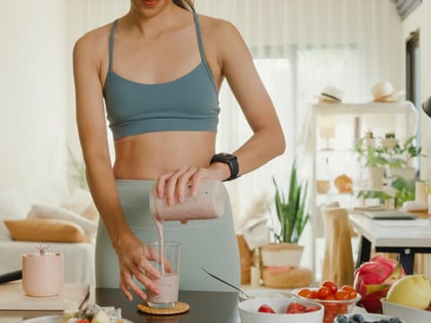 Frau im Sportoutfit macht sich Proteinshake Frau im Sportoutfit macht sich Proteinshake