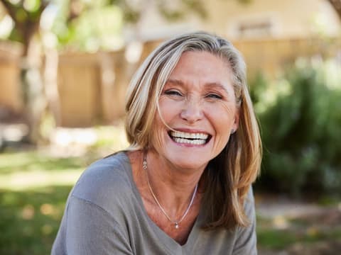 Krebsprävention durch Ernährung und Lifestyle Eine Frau im besten Alter strahlt mir einem breiten Lachen in die Kamera. Sie sieht gesund und glücklich aus.