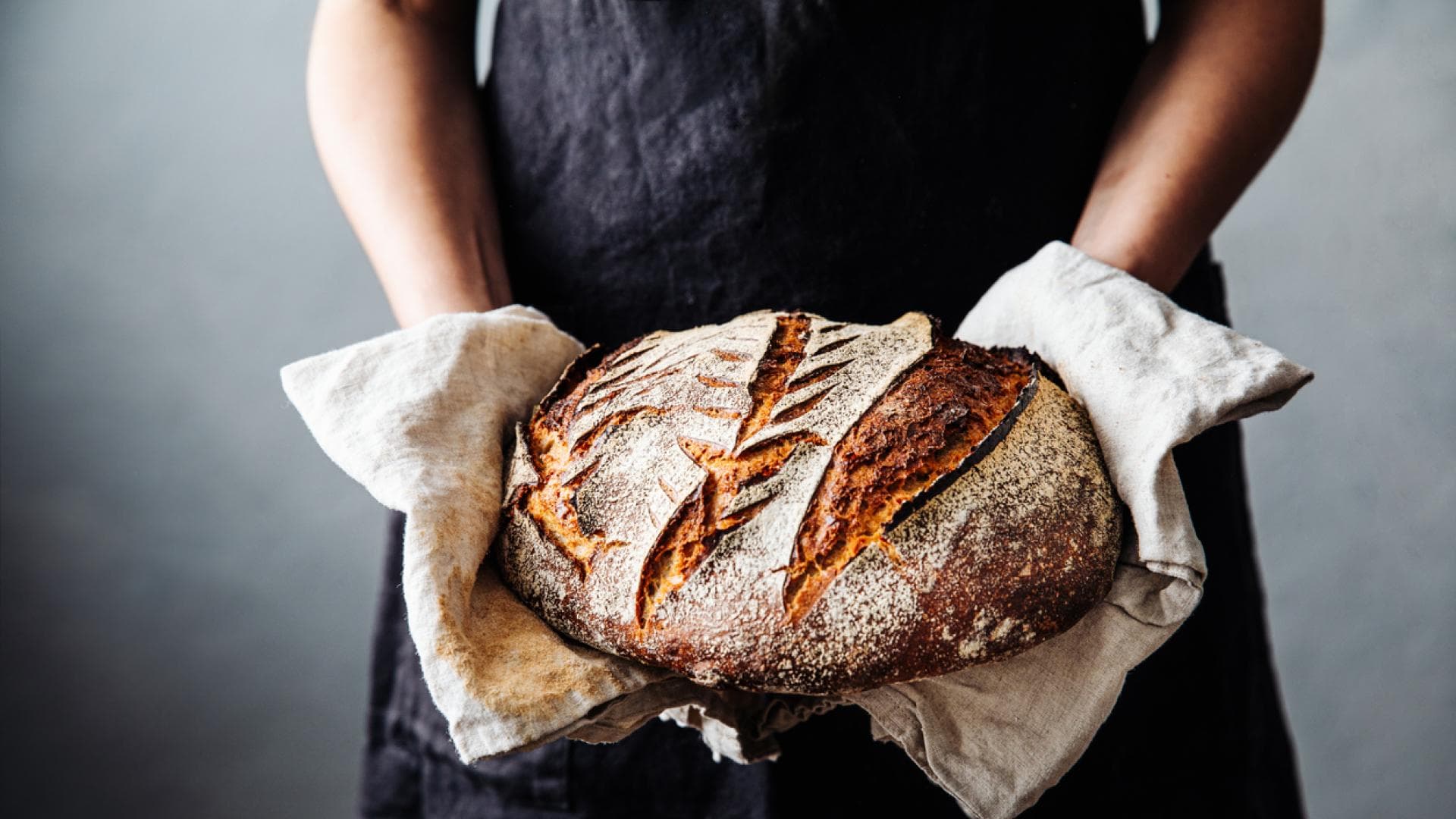 Sauerteigbrot ist lange haltbar Bäckerin hält frisches Sauerteigbrot in den Händen